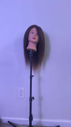 hairdresser mannequin head mounted on a tripod stand.