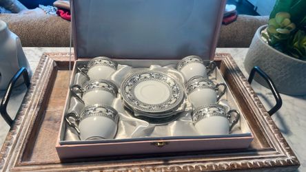 A porcelain tea set with silver-toned handles and classical decorative bands.