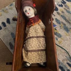 vintage porcelain doll and antique wood cradle