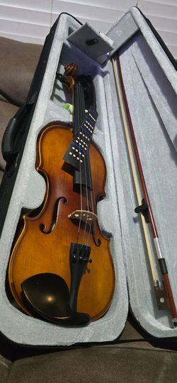 Complete violin set. It has a beautiful wooden violin. It has a black hard case with a grey interior. It has a bow. It has rosin. It has a tuner. It h