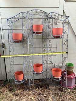 Metal plant stand outdoors with 6 pots
