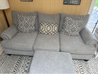 Grey fabric sofa couch with cushions and ottoman