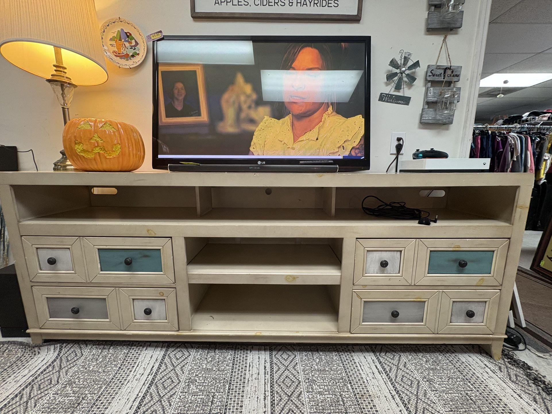 84” TV console featuring a distressed, light-colored finish and two central open shelves.