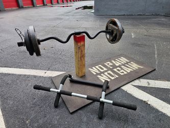 Pull up rack + 100 Pounds total. Black EZ curl bar loaded with cast iron weight plates on both ends. Plates show surface rust and wear from regular us