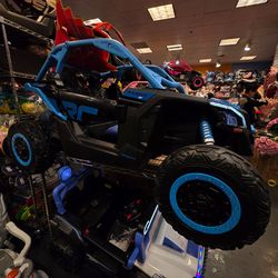A collection of children's ride-on toys, including cars, trucks, and ATVs. The toys are made of plastic and have various features such as headlights, 