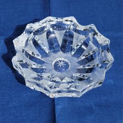 Vintage cut glass crystal ashtray with a starburst pattern. 
It is a heavy, 5" round piece with a faceted design. 