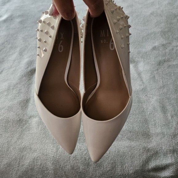 White patent pointed heels with studs.