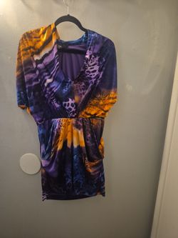 The image shows a vibrant, multi-colored abstract animal print mini dress featuring a draped V-neckline, short kimono-style sleeves, a cinched elastic