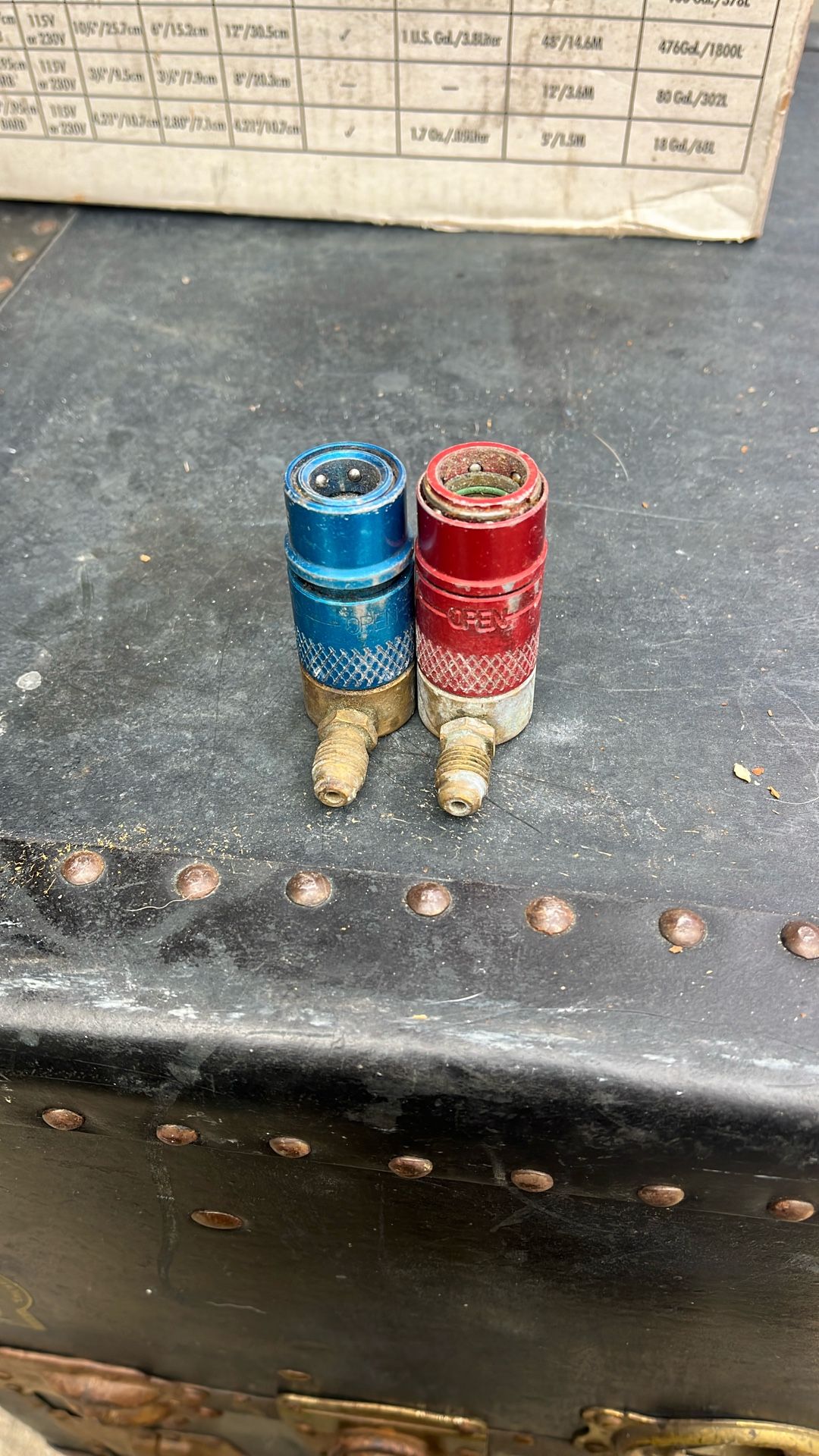 The object in the image is a red R134a quick coupler adapter, used for automotive air conditioning systems.