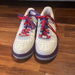 pair of Nike Air Force 1 sneakers. They are low-top sneakers with a white leather upper, purple accents on the he