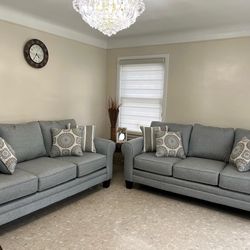 Two comfy blue/grey sofas with pillows