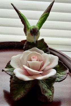 hummingbird FIGURINE perched/hovering over a pink and white rose