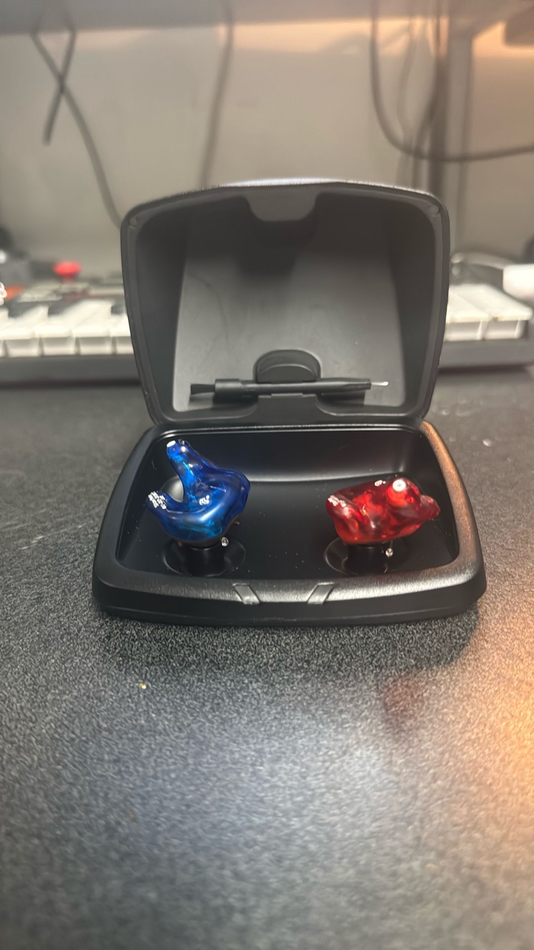 Starkey custom in-ear hearing aids along with their portable charging case. 