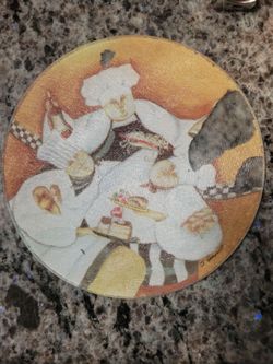 round cutting board featuring Jennifer Garant's "Al Dente" chef artwork, often produced on tempered glass