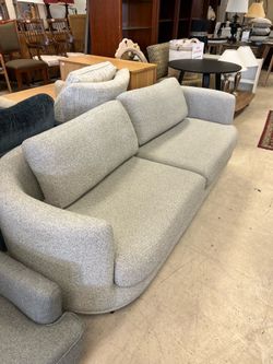 Modern gray fabric sofa featuring a light wood base and matching throw pillows with tassels - 82”