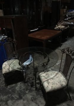 Glass topped table with 2 wrought iron chairs.