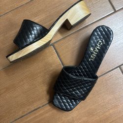 Chic black quilted mules by CHANEL. Features a natural wood heel. Ideal for stylish occasions.🖤
