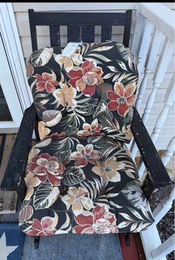 Old wooden rocker painted black with cushions.