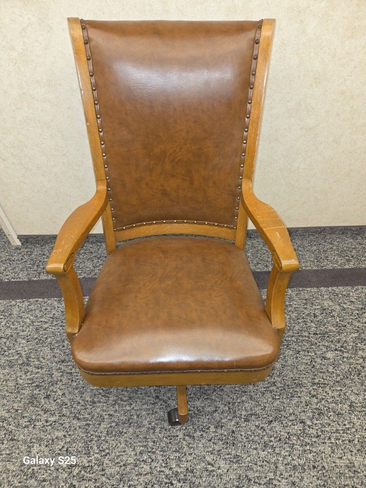 antique style brown leather office chair with a wood frame and nailhead trim whith wheels