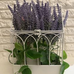 Artificial lavender plant in a decorative white metal cage.