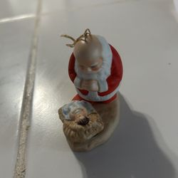 vintage 1985 "The Kneeling Santa" ornament by Roman, Inc. It depicts Santa Claus kneeling in reverence before the infant Jesus, blending secular and r