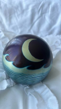 A Steven Correia art glass paperweight with a crescent moon and waves.