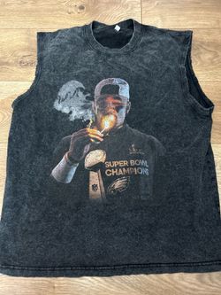 Large vintage-style, acid-wash sleeveless shirt features a graphic of Jalen Hurts celebrating a Super Bowl victory