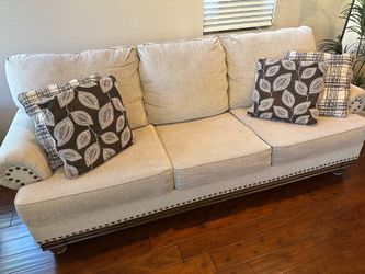 Beige sofa and love seat with nail head trim