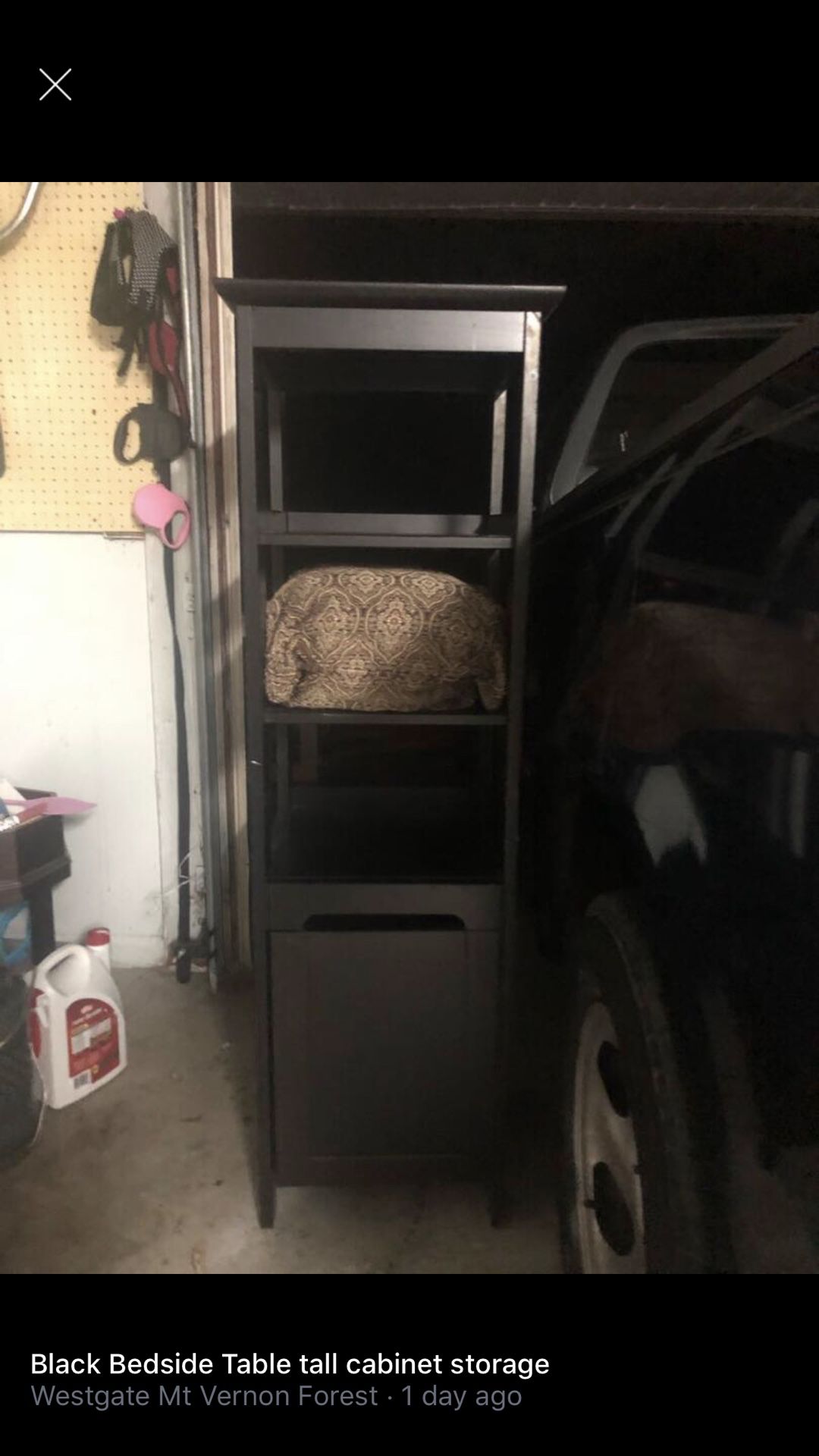 Tall black storage shelf with three levels and a cabinet