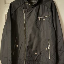 chaqueta que se muestra es de la marca INC International Concepts (I.N.C.), talla M (Medium), y está hecha de 100% Nylon en el exterior (Shell) y 100%