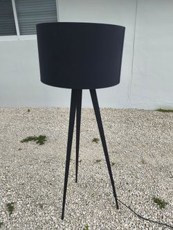 modern black tripod floor lamp with a slender three-legged metal base and a matching black drum shade
