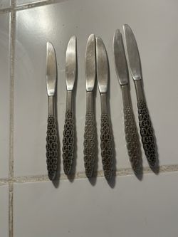 vintage International Silver Company dinner knives in the Lyon Romanesque stainless steel pattern.  Pattern: Romanesque, featuring an embossed scroll 