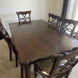 Large brown wood table with chairs and extender