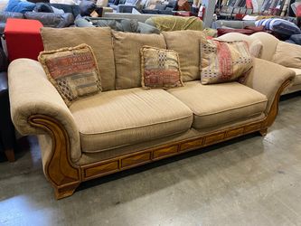 Light Brown Sofa with Carved Wood Base Detail and Contrast Pillows