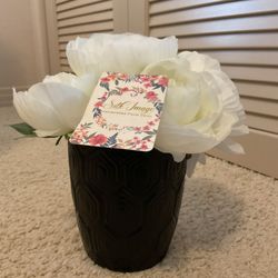 Elegant white artificial flowers in a textured black vase.