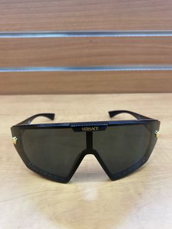 Versace sunglasses feature a shield-style design with a bold, black frame and a detachable dark blue lens
