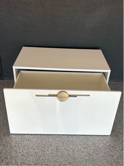 Modern white storage bin on Wheels. Circular brushed gold handle.