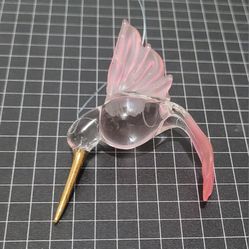 Pink and Clear Tone Hand Blown Glass Hummingbird with Gold Beak.

This product is a hand-blown glass ornament of a hummingbird with a gold beak.
