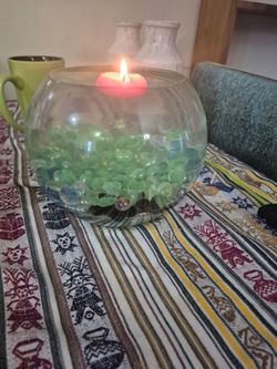 Round fish bowl with lots of glass pieces put in water and floating candles