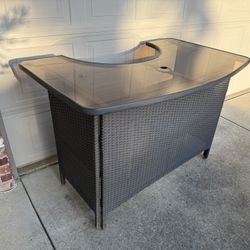 Large Sturdy resin patio bar table with glass top and metal shelf, a small area of broken weave. Perfect for holding food and serving drinks  Cash onl