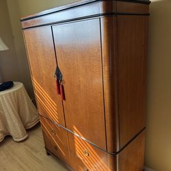 Biedermeier-style armoire featuring curly maple wood with ebonized trim