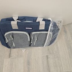 The item in the image is a duffel or shoulder bag from the Mon Chateau Luxury Collection brand. It is made of a denim-style blue and grey fabric and a