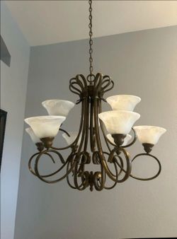 Chandelier featuring curved metal details, a bronze finish, and nine white frosted glass shades.