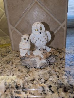 decorative collectible figurine featuring a mother snowy owl and her owlet perched on a snowy branch. 
