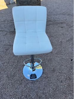 This adjustable white bar stool features a tufted PU leather seat and a polished chrome base