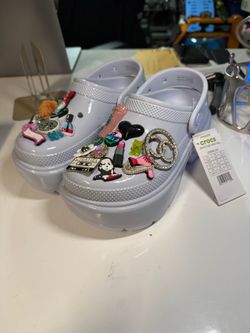 Crocs Stomp High Shine In Light Blue Platforms decorated with various charms and a chain accessory.