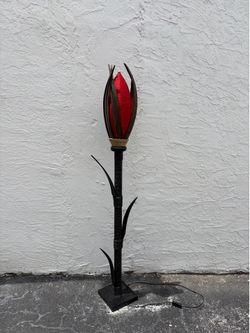 The unique floor lamp in the shape of a red tulip is made in a craft style using natural materials