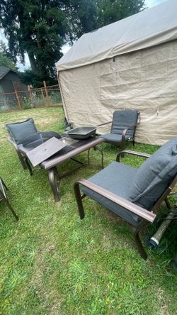 Patio set with four comfortable chairs and a square table. The table features a space for a cooler or fire pit. Everything is in good condition.