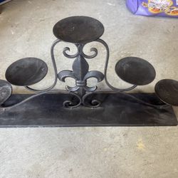 Black wrought iron candelabra or candle holder with a fleur-de-lis motif. 