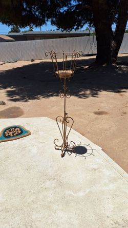 decorative wrought iron plant stand features a gold-toned finish and scrollwork details